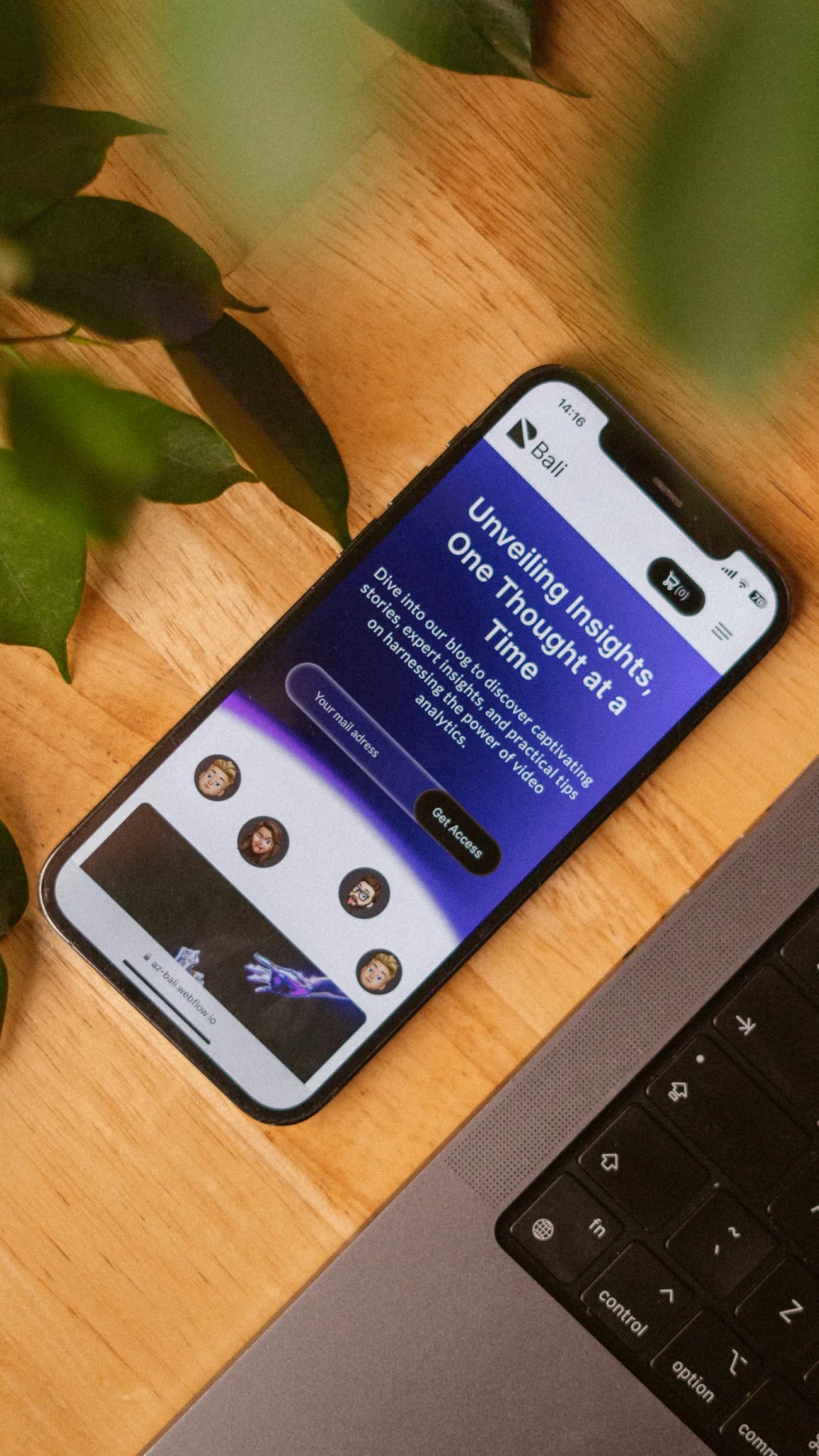 A smartphone on a wooden desk showing a landing page with an email sign-up field and a call-to-action button