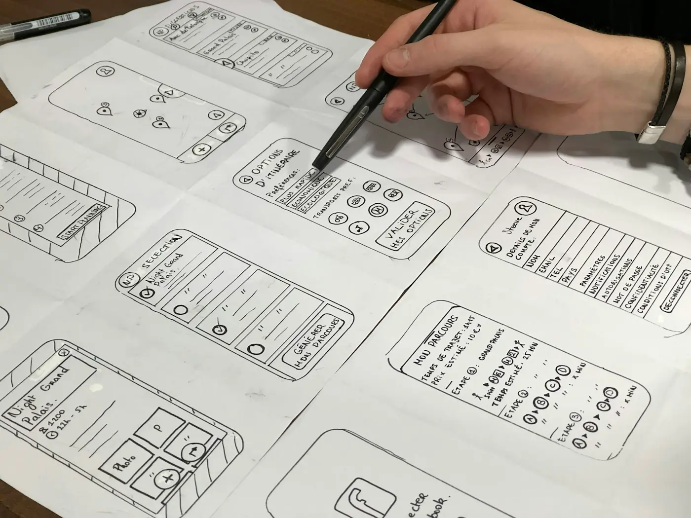 Hand-drawn wireframe sketches of app and website screens on paper