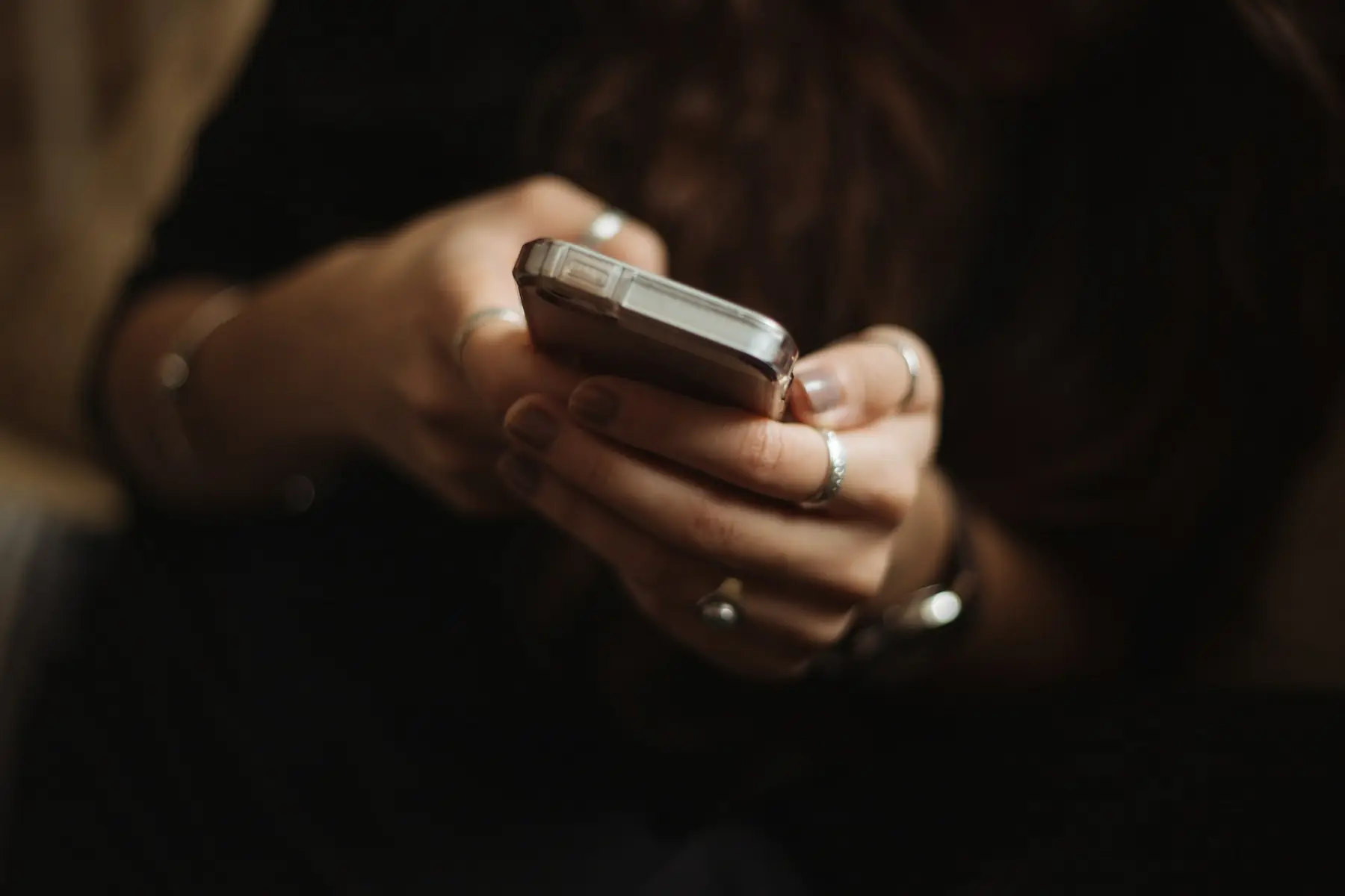 Hands typing a message on a smartphone in a dimly lit room